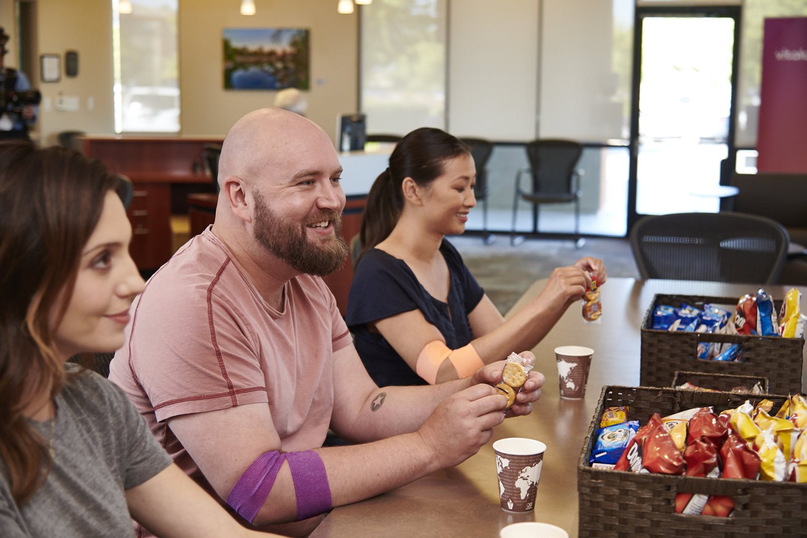 A man and two women eating snacks after donating blood